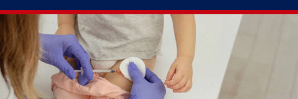 Healthcare worker in purple gloves gives a child a shot in the thigh while the child sits on a table; banner above reads 'Every unvaccinated child is evidence of a crime'.