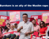 Male speaker in a white polo shirt addresses a crowd at a political rally, surrounded by supporters holding red signs reading 'ANDY FOR US'.
