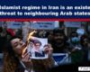 Protester burns a portrait of Iranian leaders during a rally, with others holding signs in the background.