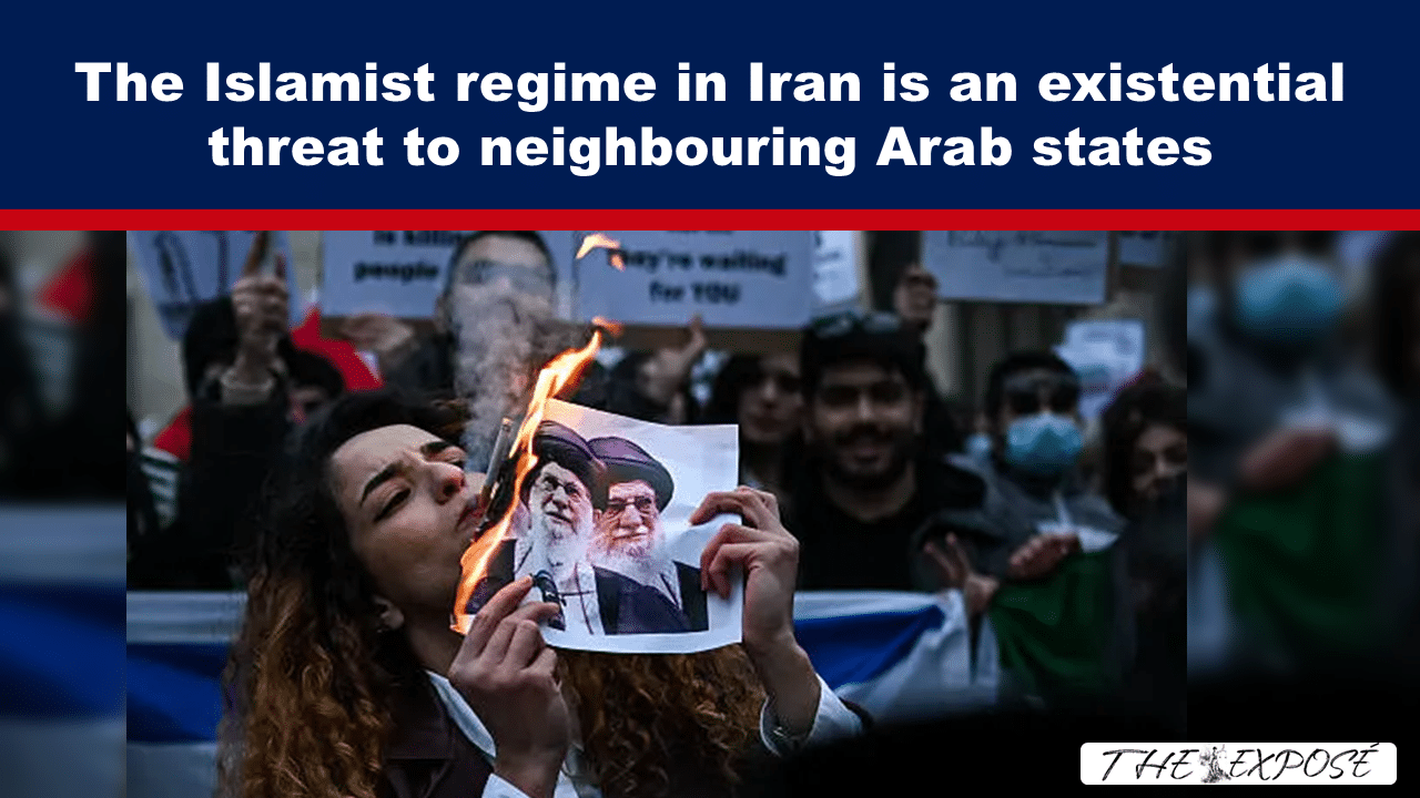 Protester burns a portrait of Iranian leaders during a rally, with others holding signs in the background.