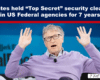 On-screen headline about a famous tech founder’s claimed top-secret security clearance; man on stage raises both hands.