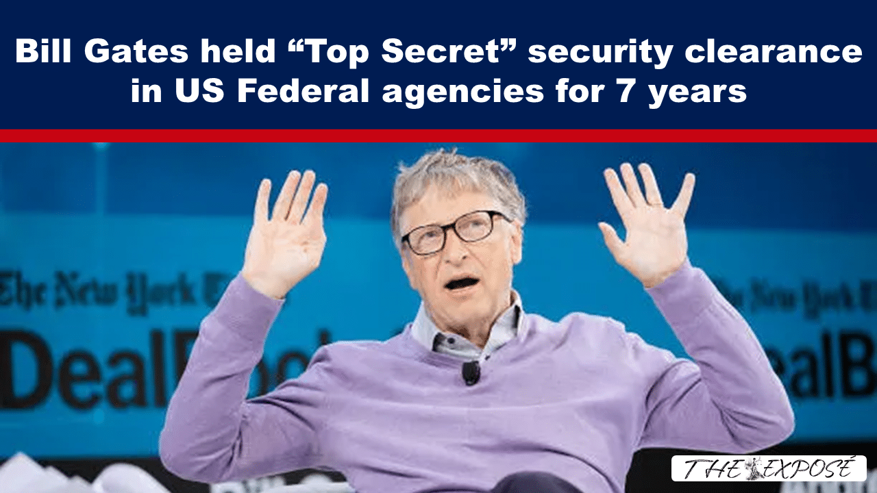 On-screen headline about a famous tech founder’s claimed top-secret security clearance; man on stage raises both hands.