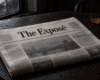 The Exposé newspaper on a dark wooden table beside a rain-streaked window.